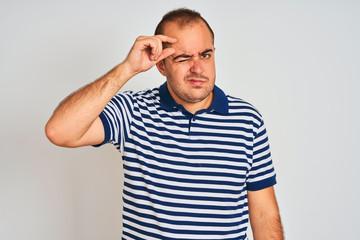 Fototapeta premium Young man wearing casual striped polo standing over isolated white background pointing unhappy to pimple on forehead, ugly infection of blackhead. Acne and skin problem