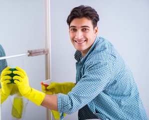 The young man cleaning mirror at home hotel