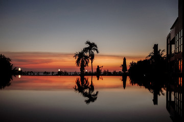 Obraz na płótnie Canvas Black Palms silhouettes at orange sunset sky