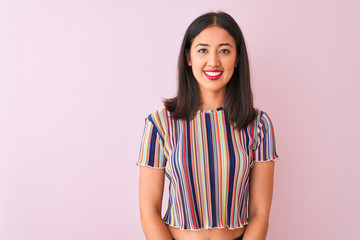 Young chinese woman wearing colorful striped t-shirt standing over isolated pink background with a happy and cool smile on face. Lucky person.