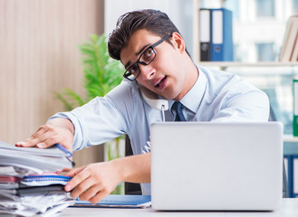 Businessman with excessive work paperwork working in office