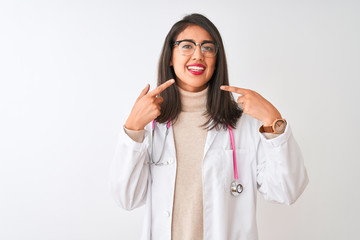 Chinese doctor woman wearing coat and pink stethoscope over isolated white background smiling cheerful showing and pointing with fingers teeth and mouth. Dental health concept.