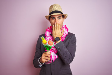 Businessman wearing suit hat hawaiian lei drinking cocktail over isolated pink background cover...