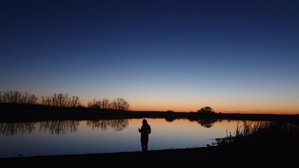 silhouette of woman on lake at sunset