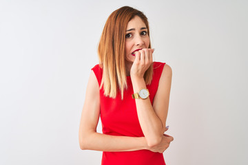 Redhead businesswoman wearing elegant red dress standing over isolated white background looking stressed and nervous with hands on mouth biting nails. Anxiety problem.