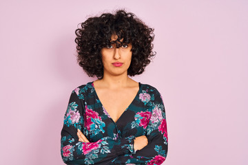 Young arab woman with curly hair wearing floral dress over isolated pink background skeptic and...