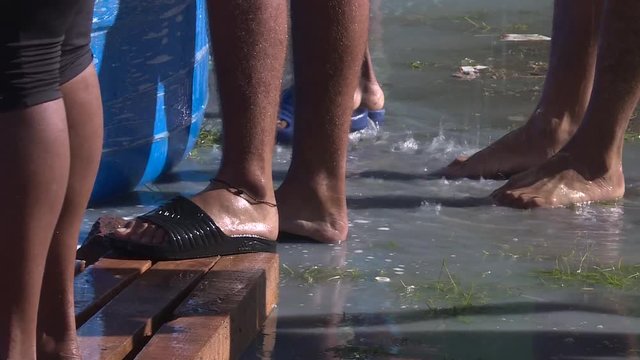 close up, migrants feet wet while they are washing clothes