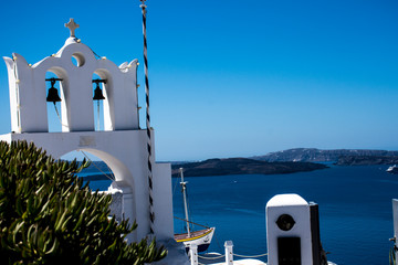 bell tower in oia greece, white is combined with the blue of the sky