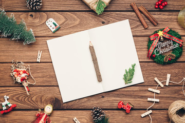 Top view of blank notebook on wood  background with xmas decorations. Mockup Christmas background with notebook for wish list or to do list. Flat lay with copy space.