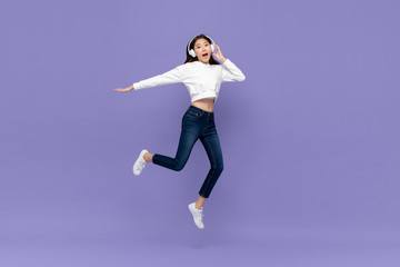 Asian woman jumping and listening to music on headphones