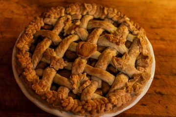 Selective focus closeup of a homemade apple pie with a beautiful decorative lattice crust with autumn leaf pastry cutouts, baked golden brown and ready to serve for a special holiday meal 
