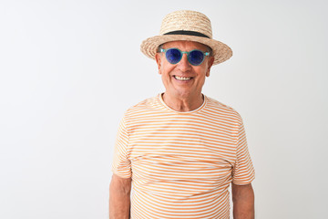 Senior man wearing striped t-shirt sunglasses and sumer hat over isolated white background with a happy face standing and smiling with a confident smile showing teeth