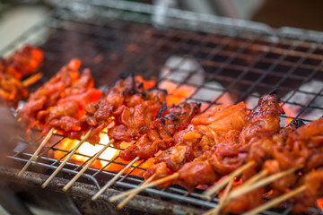 Naklejka premium The blurred background of grilling chicken on a charcoal grill, with the heat of the flame from the oil of the meat, spreading smoke and a fragrant flavor from the food smell.