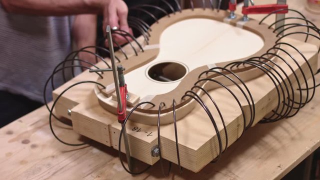 Luthier glues a guitar with spring clamps