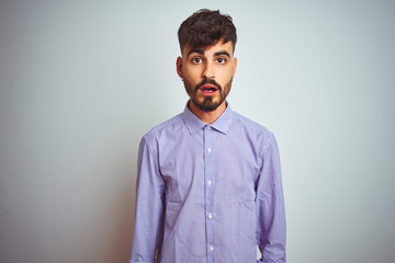 Fototapeta premium Young man with tattoo wearing purple shirt standing over isolated white background afraid and shocked with surprise expression, fear and excited face.
