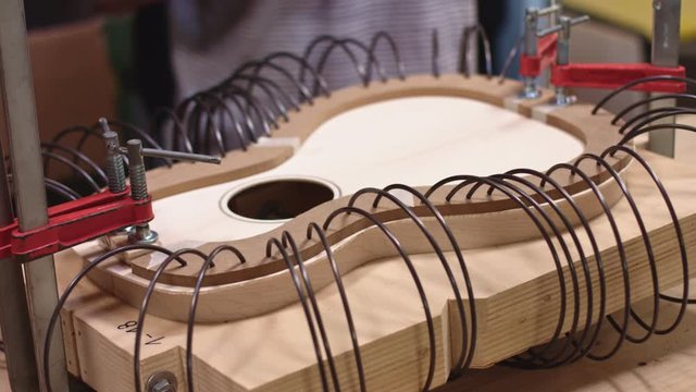 Guitar maker adding spring clamps to the guitar body