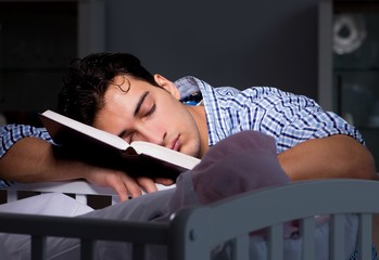 Young student doing homework and looking after newborn baby