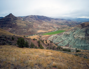 Breathtaking views of the grey-blue badlands and the scenic John Day River Valley and Mountains from the rustic Blue Basin Overlook Trail at the John Day Fossil Beds Sheep Rock Unit in Kimberly Oregon
