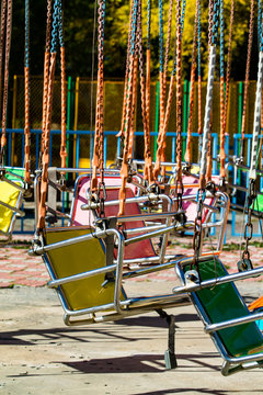 Empty carousel metal seat. Amusement park concept in a city park. Sunny day.