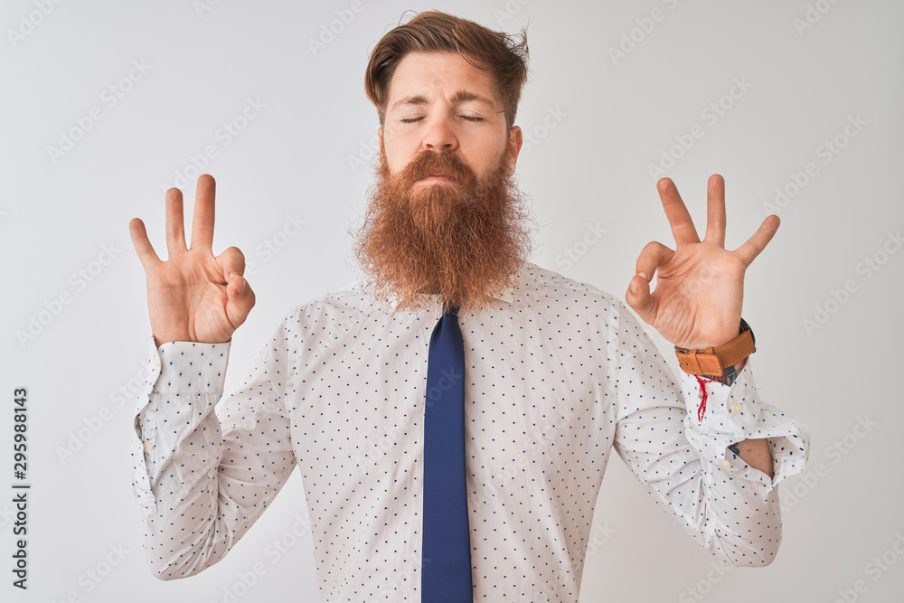 Poster Young redhead irish businessman standing over isolated white background relaxed and smiling with eyes closed doing meditation gesture with fingers. Yoga concept.