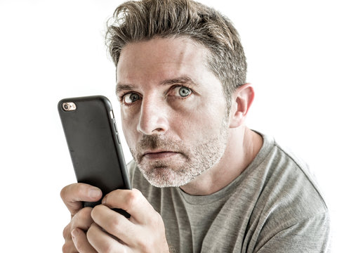 freak and weird looking man using mobile phone watching something online in sick intense face expression in internet and social media addiction concept isolated