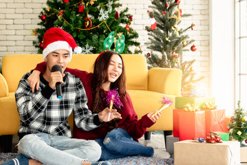 Obraz na płótnie Canvas Young Asian couples sing a song celebrating Christmas party with happy in home. Copy Space.