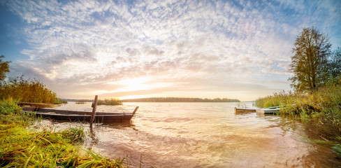 Panoramic landscape with sunrise in a water body with boats