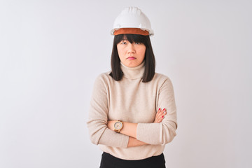 Young beautiful Chinese architect woman wearing helmet over isolated white background skeptic and nervous, disapproving expression on face with crossed arms. Negative person.