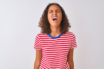 Young brazilian woman wearing red striped t-shirt standing over isolated white background angry and mad screaming frustrated and furious, shouting with anger. Rage and aggressive concept.