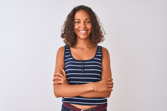 Young brazilian woman wearing striped t-shirt standing over isolated white background happy face smiling with crossed arms looking at the camera. Positive person.