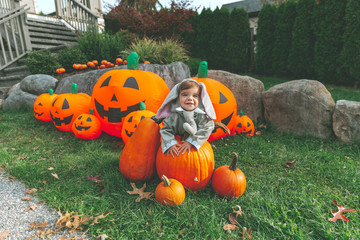 A baby dressed as an elephant for Halloween, standing amidst Halloween decorations. 