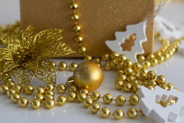 Christmas present and gold ornaments on a white background