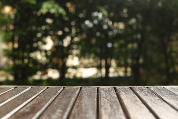 wooden floor background for products placement copy space. wood table in a garden. forest bokeh light background. warm tone image