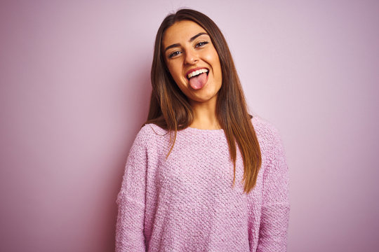 Young beautiful woman wearing casual sweater standing over isolated pink background sticking tongue out happy with funny expression. Emotion concept.