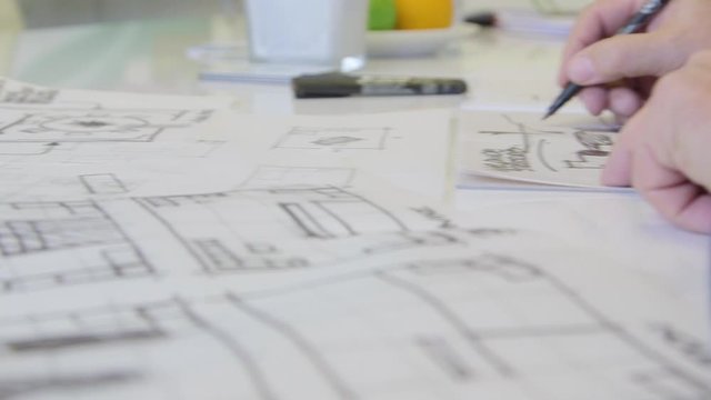 Designer architect drawing sketches with pen panning shot.