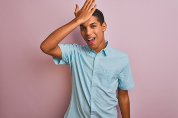 Young handsome arab man wearing blue shirt standing over isolated pink background surprised with...