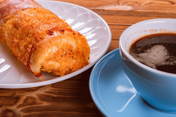 side view bread with bacon and shredded pork and cup of coffee nearby
