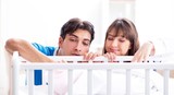 The happy young family at baby bed cot