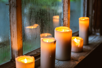 beautiful background with raindrops on the window and burning candles.