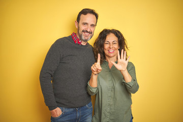 Beautiful middle age couple over isolated yellow background showing and pointing up with fingers number six while smiling confident and happy.