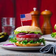 Burger on a plate with American flag. Wooden background. Close up.