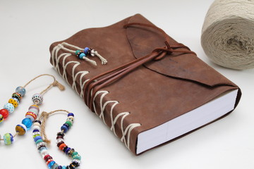 leather cover of handmade book with handmade bead on white background