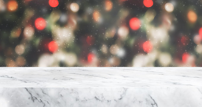 marble table top with abstract blur christmas tree red decor ball and snow fall background with bokeh light,winter Holiday backdrop,Mock up banner for display of product or promotion