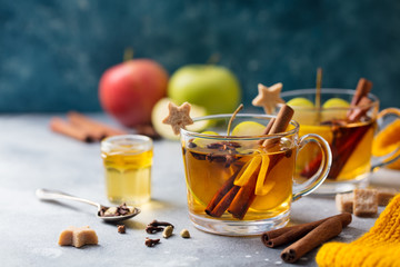 Apple mulled cider with spices in glass cup. Grey stone background. Copy space.