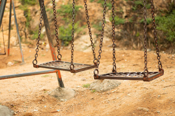 Selective focus of Empty spooky swing in desolate park.