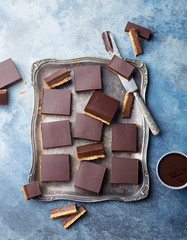 Chocolate caramel slices, bars, millionaires shortbread. Blue background. Top view.