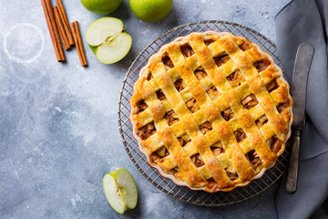 Apple pie with caramel sauce on a cooling rack. Grey background. Copy space. Top view.