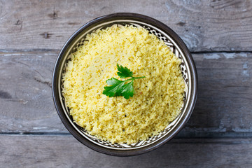 Couscous in bowl. Wooden background. Close up. Top view.