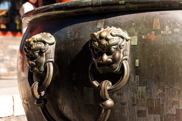 Bronze lion handles on the bronze water tank in side of the Forbidden city, the main buildings of...