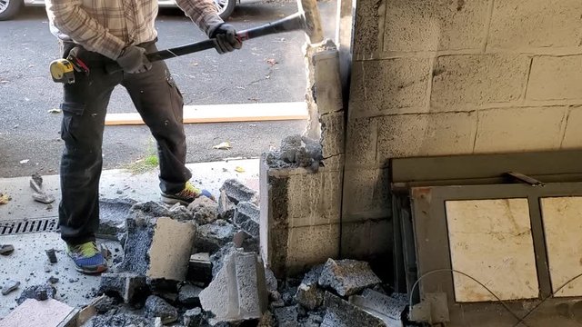 Demolition of concrete wall. Breaking concrete blocks with sledge hummer